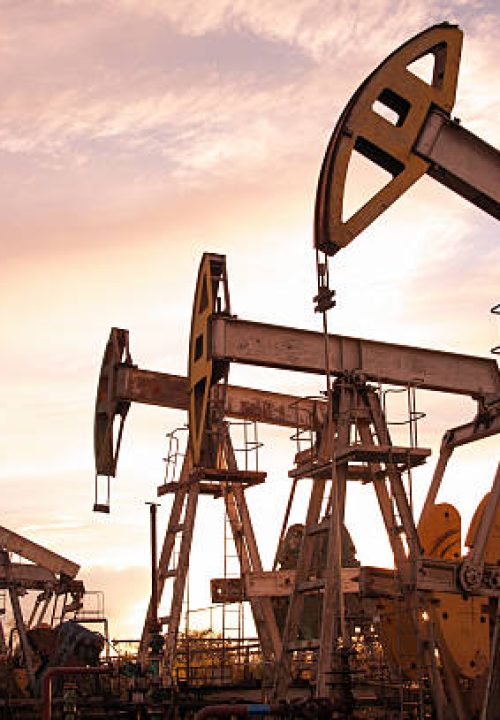 Oil pump jacks at sunset sky background. Toned.
